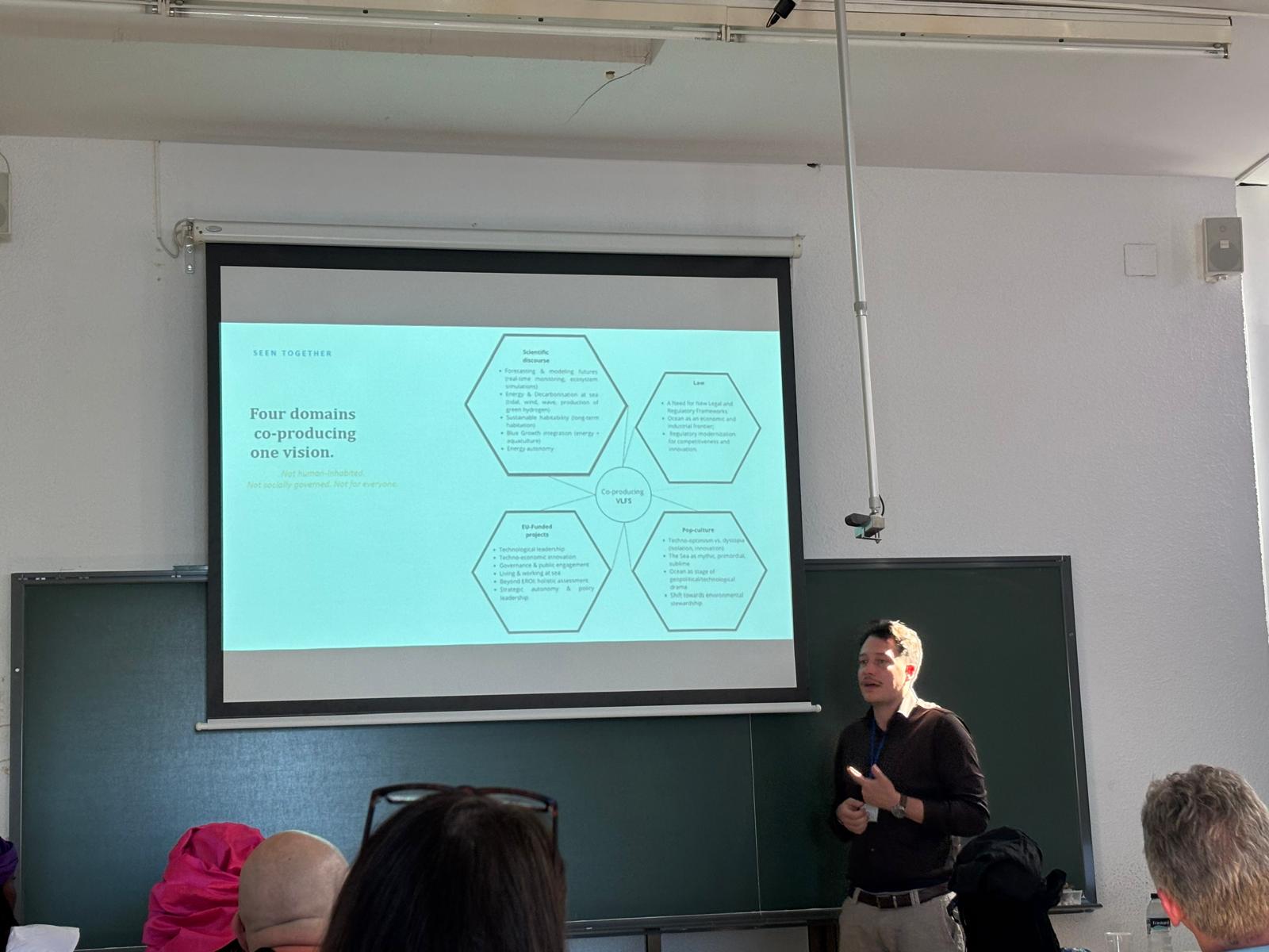 Wide view of a lecture hall during a presentation on four domains co-producing a vision for the sea